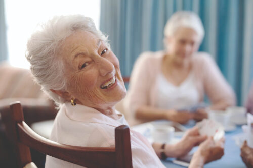 Zwei ältere Damen sitzen am Wohnzimmertisch und spielen Karten